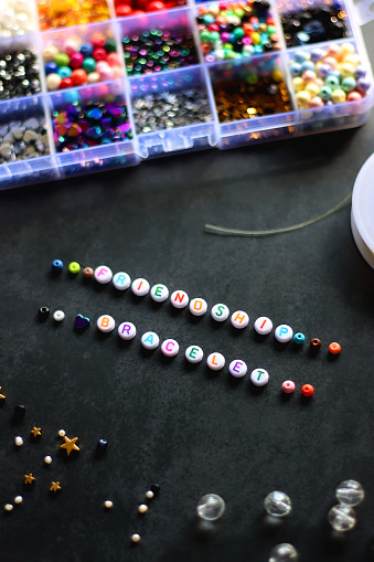 Friendship bracelet letter beads and various other jewelry making supplies on dark background. Selective focus.