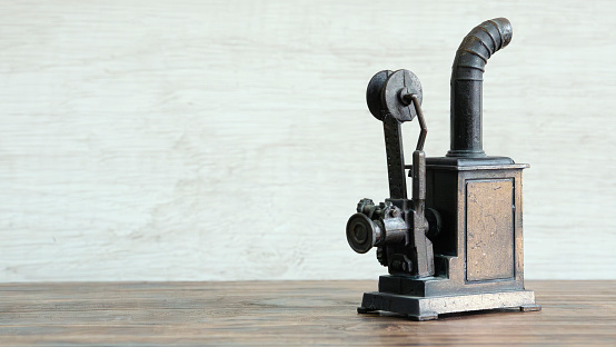 Old manual coffee grinder. Brick wall as a background with scattered coffee beans on the table