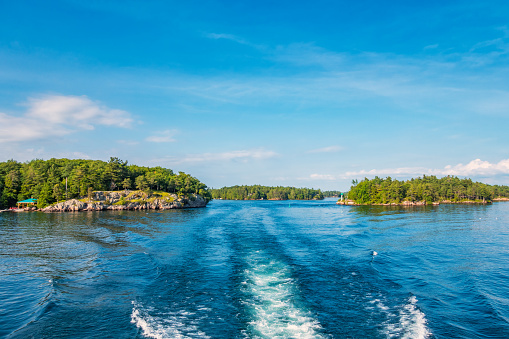 Tour boat wake in Thousand Islands National Park located on the St Lawrence River between Canada and the USA.