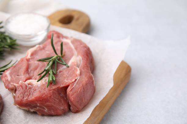 istock Fresh raw meat with rosemary on light table, closeup. Space for text 1694446533