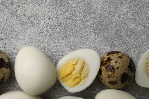 istock Peeled and unpeeled hard boiled quail eggs on grey table, flat lay. Space for text 1694455844