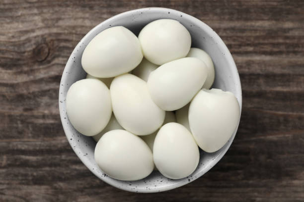 istock Many peeled boiled quail eggs in bowl on wooden table, top view 1694456380
