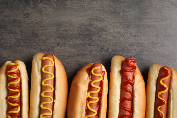 istock Delicious hot dogs with mustard and ketchup on grey table, flat lay. Space for text 1694457489