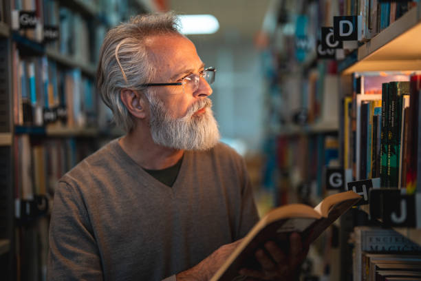 istock Senior Caucasian Male Reading A Book In A Library 1694509361
