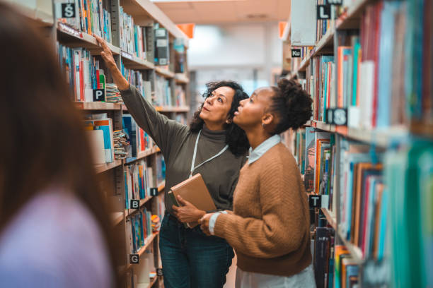 istock Hispanic Student Searching For A Book With A Librarian 1694509377
