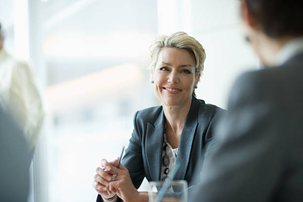 sorridente mulher de negócios em reunião - businessman mature adult 50s men imagens e fotografias de stock