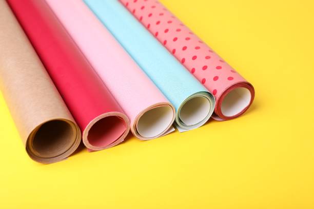 istock Rolls of colorful wrapping papers on yellow background, closeup 1694517741