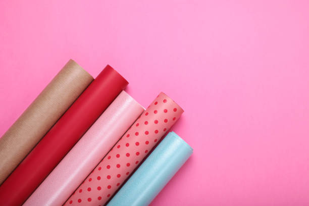 istock Rolls of colorful wrapping paper on pink background, flat lay. Space for text 1694518484