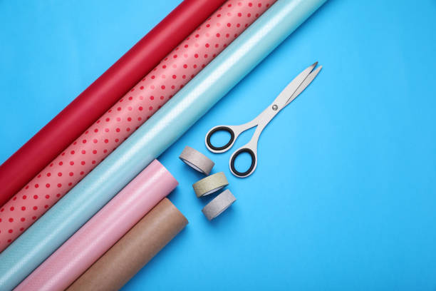 istock Rolls of wrapping papers, scissors and ribbons on light blue background, flat lay. Space for text 1694519002