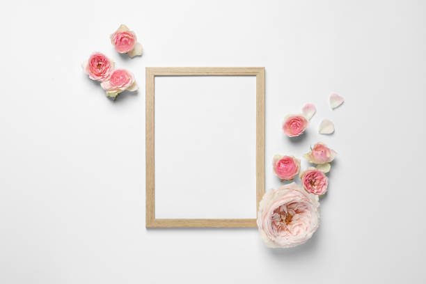 istock Empty photo frame and beautiful flowers on white background, flat lay. Space for design 1694519004