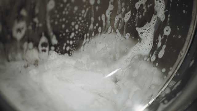 Foamy washing machine with different clothes., slow motion