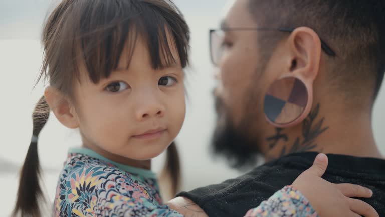 Asian father and cute little daughter walk by the sea enjoying vacation together.