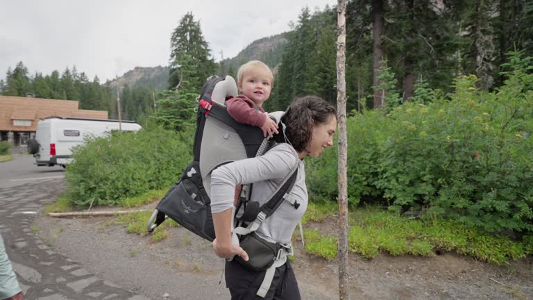 Active mother prepares to hike with young son in a backpack carrier