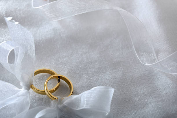 istock Two gold rings tied with ribbon on white cloth top 1694570911
