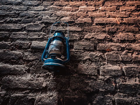 A storm lantern hangs on a dirty brick wall
