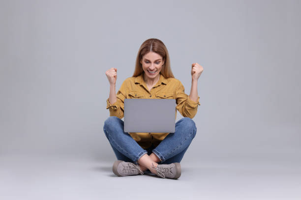 istock Emotional woman with laptop on light grey background 1694602676