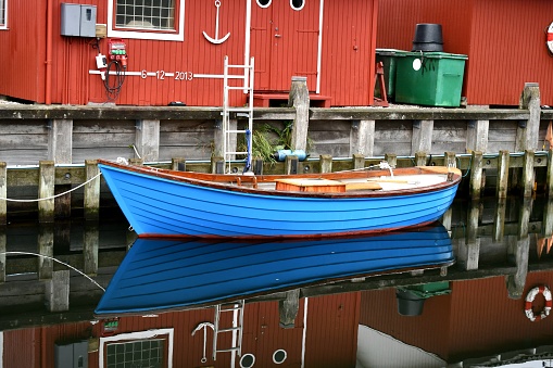 Reflections of a blue rowboat and other buildings in a harbor in Roskilde, Denmark