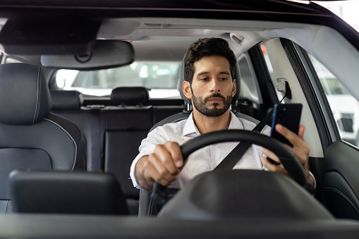 Crowdsourced taxi driver using a mobile app on his cell phone while driving -mobility as a service concepts