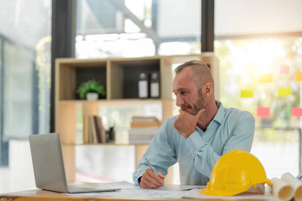 istock Caucasian or engineer male architect examining document on laptop for architectural plan 1694632626