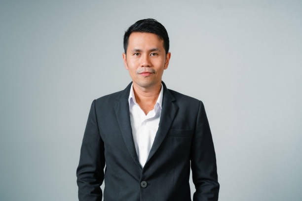 istock Asian businessman in suit with looking at camera standing studio isolated on gray background, young asian business man is manager or executive smiling and having confident is positive with success. 1694671222