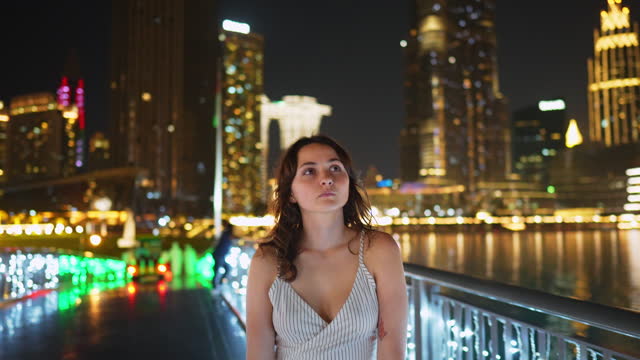 Woman walking in Dubai near Burj Khalifa and Dubai fountain at night