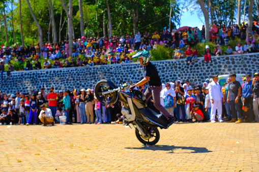 Bandung, West Java, Indonesia - 17 August, 2023 : A stuntman performs a freestyle stunt using a motorbike at the Indonesia's 78th independence day festival, performance with a lively crowd.