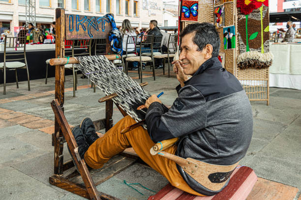 Cuenca, Ecuador - October 8, 2022: A man weaves a scarf or Makana using the ICAT technique from cotton threads. The design is traditional from the canton of Gualaceo, Azuay province, Ecuador.