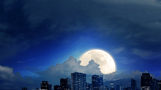 Skyscrapers and modern buildings with a full moon in the night background