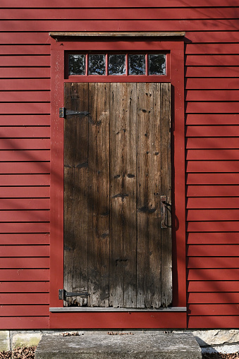 a painted red barn with white roof and double doors with grass field