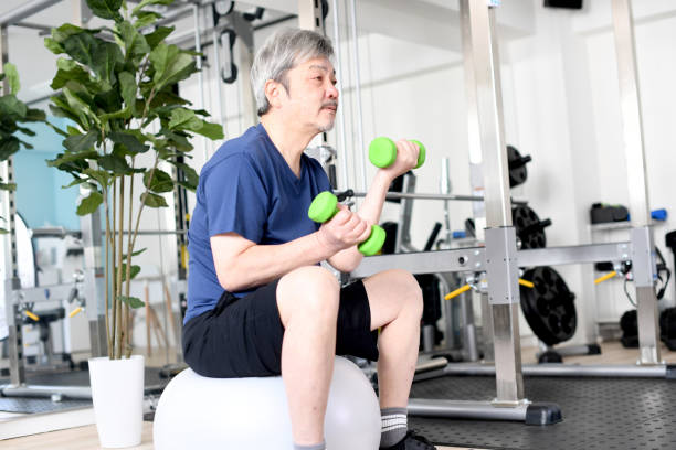 istock White-haired Asian senior man doing dumbbell training while riding an exercise ball at the gym 1694760124