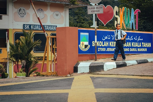 Pahang, Malaysia – September 23, 2022: A young schoolboy in front of a modern building with a heart-shaped sign adorning the facade in Pahang