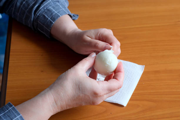 istock Hands of an elderly woman showing a white boiled egg 1694810320