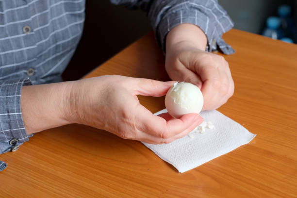 istock Hands of an elderly woman showing a white boiled egg 1694810345