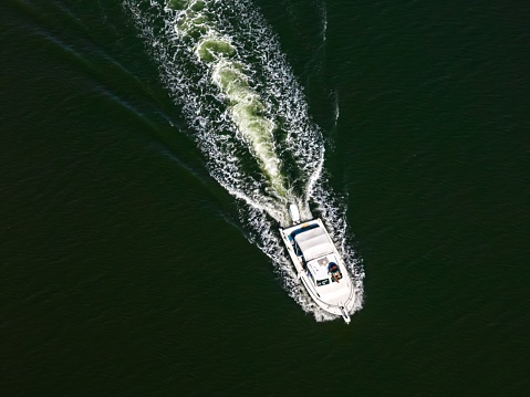 An aerial view of a white fishing boat in a bay in Brooklyn, New York on a sunny day