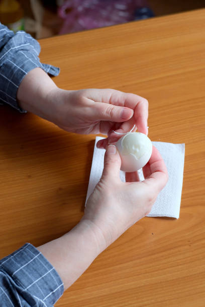 istock Hands of an elderly woman showing a white boiled egg 1694814460