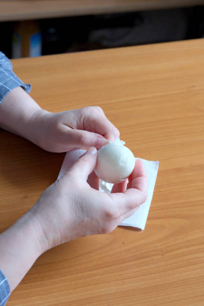 istock Hands of an elderly woman showing a white boiled egg 1694814496