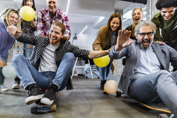istock Cheerful freelancers having fun during skateboard competition at casual office. 1694815188