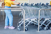 Woman taking a shopping cart in a supermarket parking lot