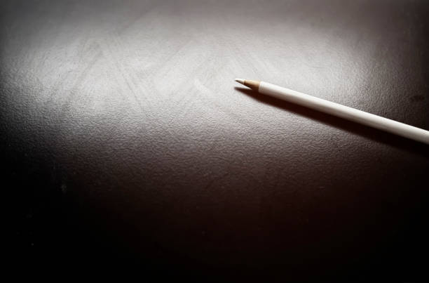 istock A white pencil on a white-gray-black area with a bright light. 1694867048
