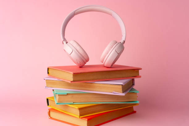 istock Pink headphones on a book on blue background 1694872470