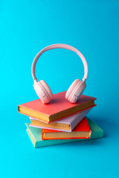 istock Pink headphones on a book on blue background 1694877055