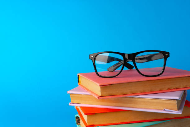 istock Reading glasses on stacked books against blue background 1694880926
