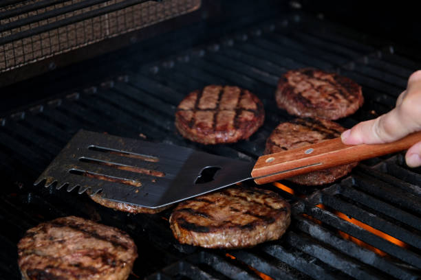 istock Barbecuing plant based Impossible Burger patties on electric grill semi close up shot panning over spatula flipped and grilled brown seasoned burger patties 1694899351