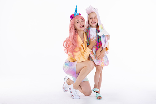 Adorable modern mommy and preschooler kid in funny clothes standing on white background in studio isolated posing while shooting process vacation concept.