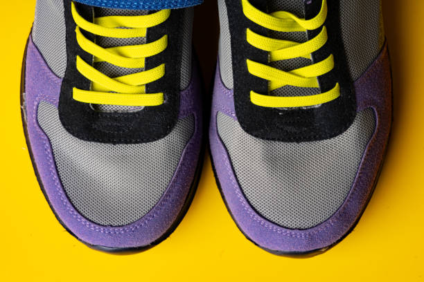 istock Violet-blue female sneakers on yellow studio background 1694910435