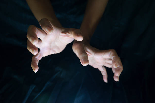 istock Hand gestures performing magic on a black background against light and dark shadow. 1694919301