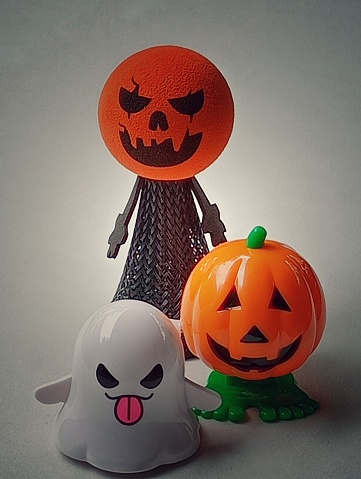 Pumpkins and ghost are standing in the dark.