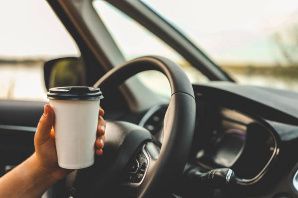istock Paper cup with coffee in hand, traveling by car 1694939855