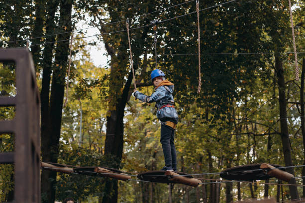 adolescent dans un parc d’aventure en plein air en passant un parcours d’obstacles. parc d’accrobranche - high up obstacle course ropes course teenage boys photos et images de collection