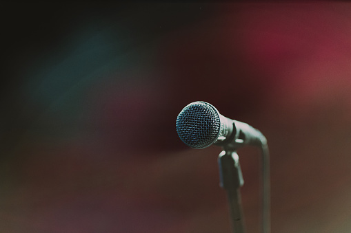 Microphone on a stand on stage in the dark colors. Close-up view.